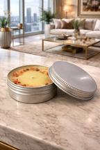 Two metal tins on a marble surface with a cityscape in the background